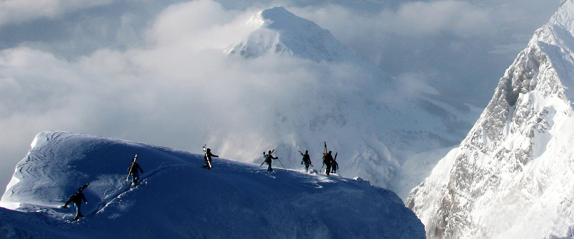 Skitourengeher auf ausgesetzten Grat im Licht-Schattenspiel beim Bergsteigen.